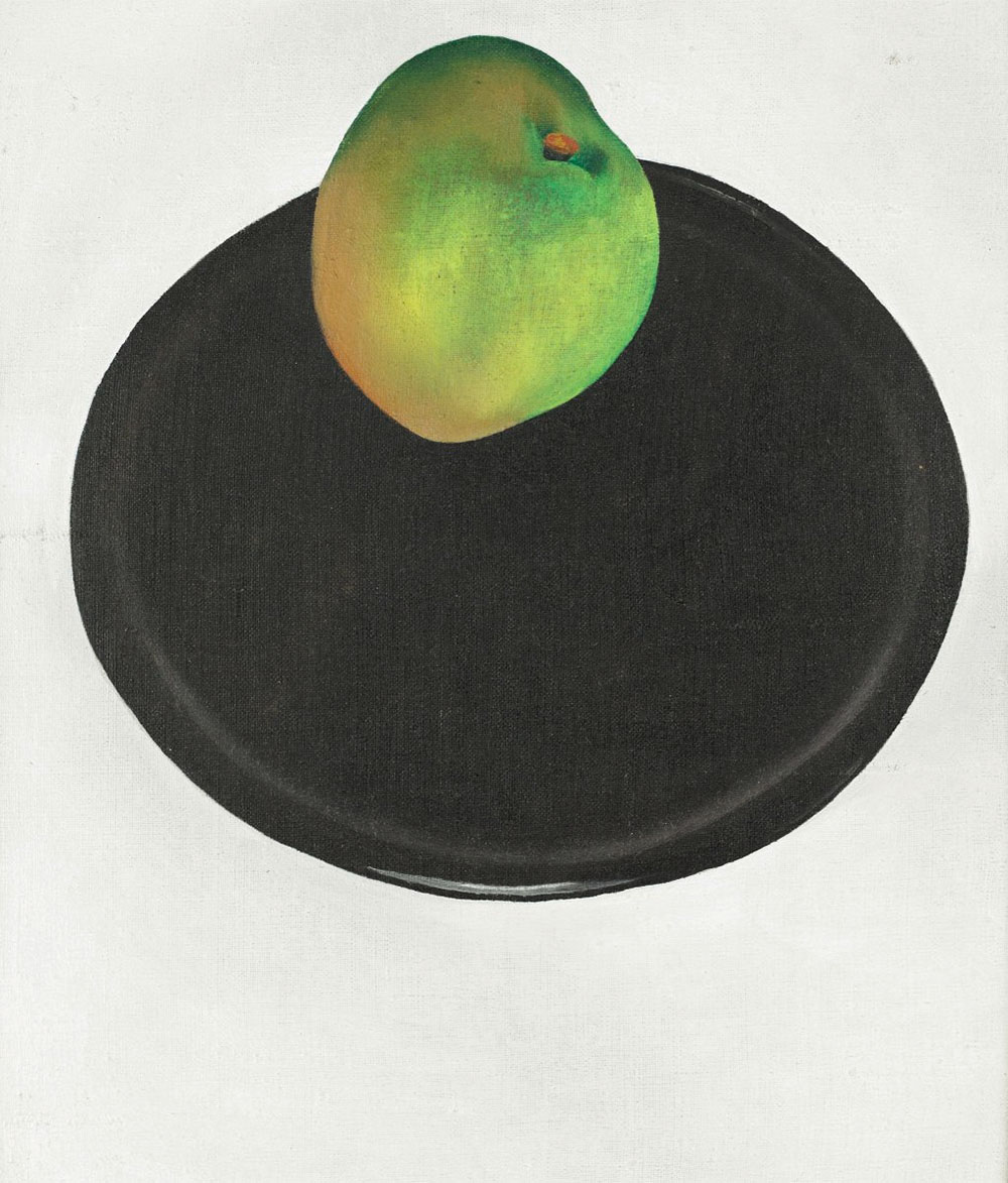 A lovely green apple which seems almost to float above a pitch-black plate, all on a white backdrop.